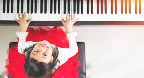 Little pianist Little asian girl happy to play piano piano stock pictures, royalty-free photos & images