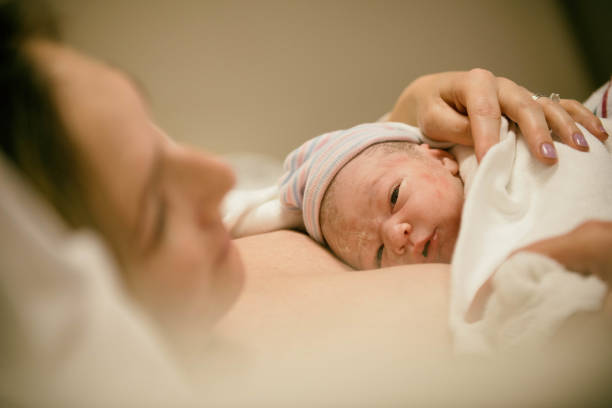 New born opening eyes for the first time after birth Young family birthing a baby in the hospital and enjoying baby's first few moments. maternity ward stock pictures, royalty-free photos & images