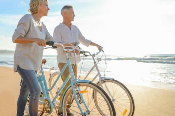 istock Mature couple walking their bicycles along the beach. 974368984