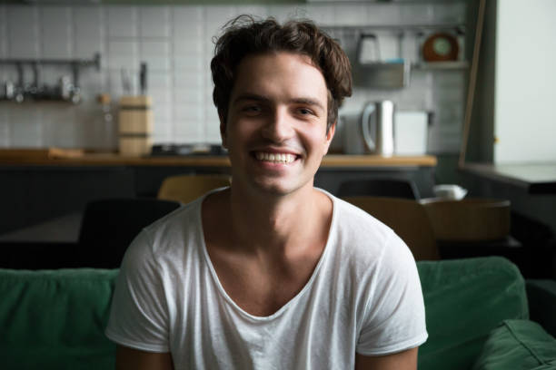 istock Smiling man looking at camera sitting on kitchen sofa, portrait 974371470