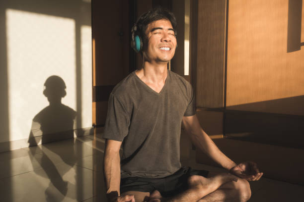 男瞑想ヨガ ロータス ポーズ目閉じた家の床の上に座って - lotus position audio ストックフォトと画像