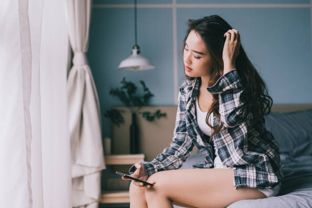 istock Woman sitting on her bed using smartphone 974377230