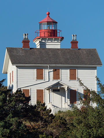 Newport, Oregon, USA - June 1, 2018: The Yaquina Bay Lighthouse is located in Newport, Oregon where it is listed in the National Register of Historic Places. Built in 1871, it was active for only a few years due to the building of Yaquina Head Lighthouse located about 3 miles north of Yaquina Bay. This photo shows the closed shutters over the windows.