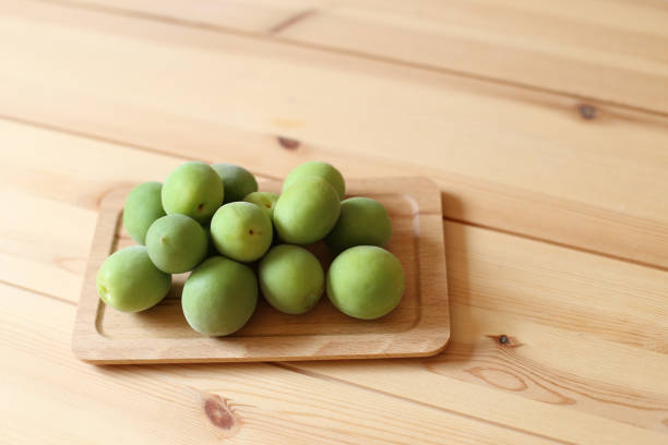 istock Green plum fruits on wooden table 974475314