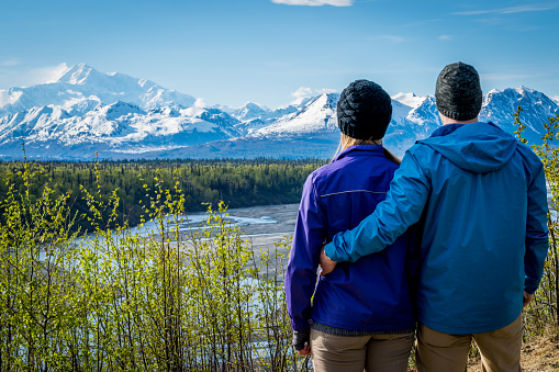 Young couple holding each other and standing in front of mount Denali formerly mount Mckinley, Alaska