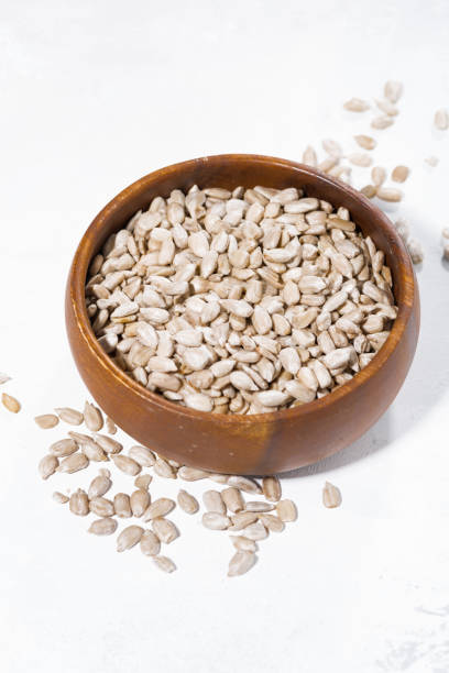 istock bowl with sunflower seeds on white background, vertical 974602138