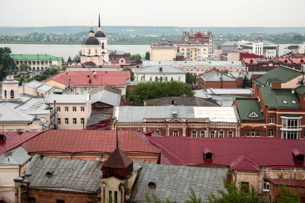 A view from above of an ancient city with an Orthodox church, roofs of various colors, a river on a warm summer day
