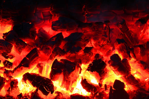 istock The fire element of nature background. Fire flame with burning logs. Burning firewood and ember close up. Burning dark red-orange background. 974627092