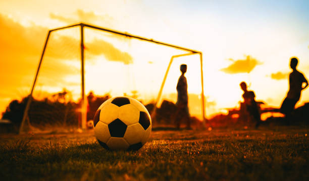 eine aktion sport bild einer gruppe von kind spielen fußball für übung in vor sonnenuntergang. - soccer teenager team ball stock-fotos und bilder