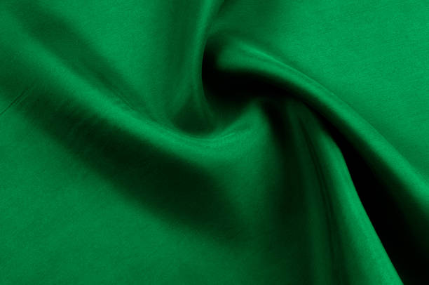 istock Background texture, pattern. Thick thick silk fabric is green. This satin fabric is ideal for creating a smooth flow in design, it has a liquid drape and exquisite shine. 974627436