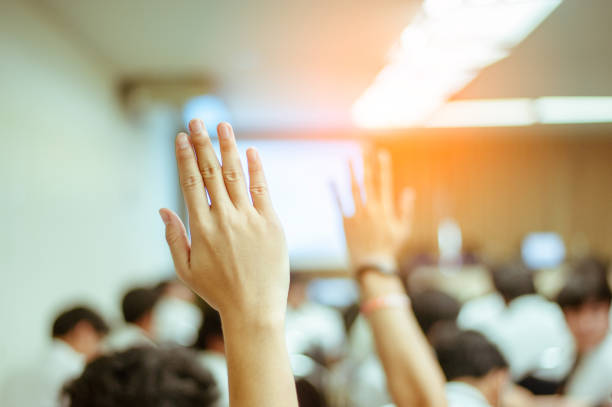 businessman raising hand during seminar. Businessman Raising Hand Up at a Conference to answer a question. stock photo