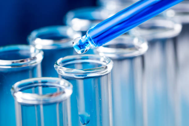 istock Pipette with blue liquid water drop fall in test tube in laboratory. 974631916