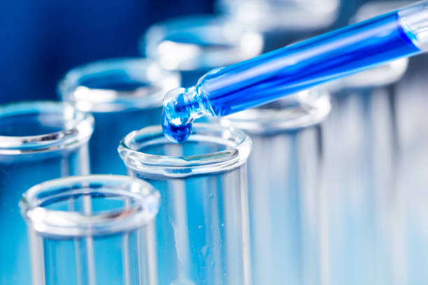 istock Pipette with blue liquid water drop fall in test tube in laboratory. 974631920