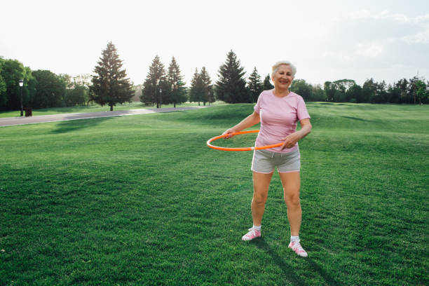 istock elderly woman does the exercise with hula hoops 974637044