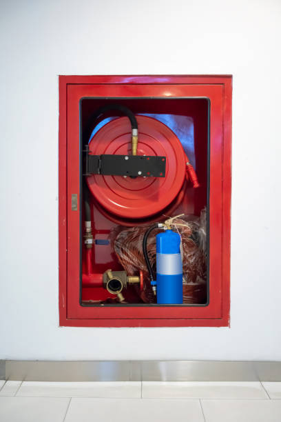 istock Fire Hose Cabinet on orange bricks floor against white concrete wall. 974640666