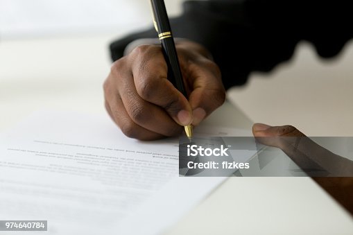 istock Close up of black worker signing legal documentation 974640784