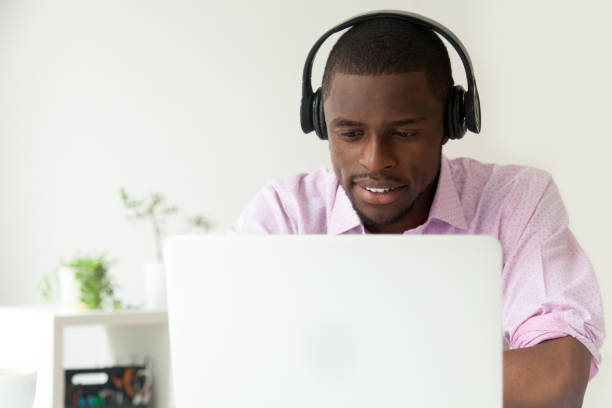 happy african american watching webinar at laptop in office - center occupation headset on the phone imagens e fotografias de stock