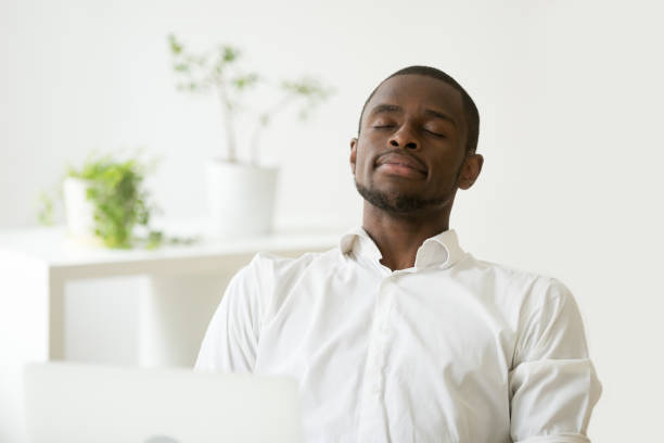 istock Satisfied African American worker meditating at workplace managi 974640822