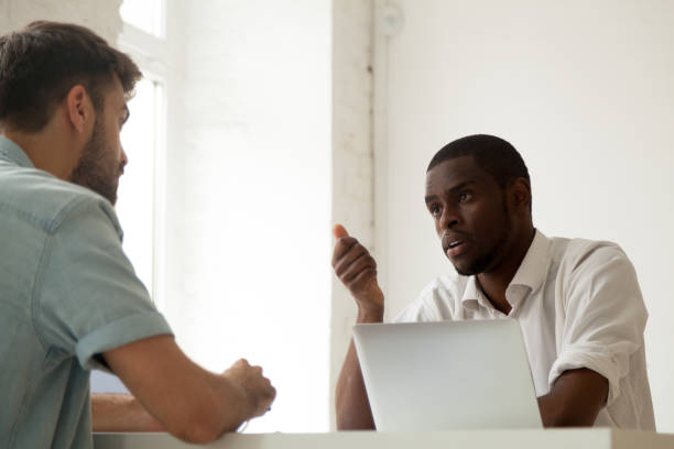 istock Serious black worker talking to Caucasian colleague during busin 974640894