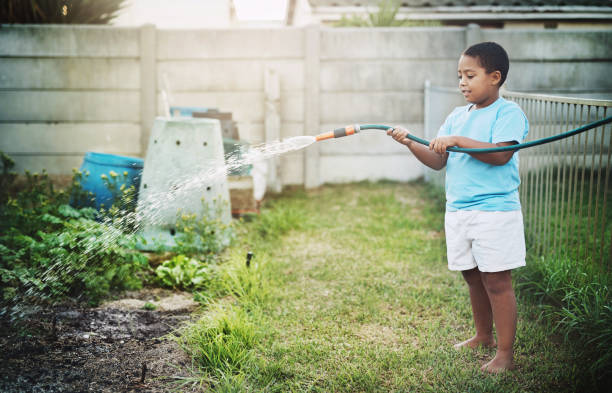 He'll grow up with a passion for plants Shot of a little boy using a hose pipe to water the garden outdoors green fingers stock pictures, royalty-free photos & images