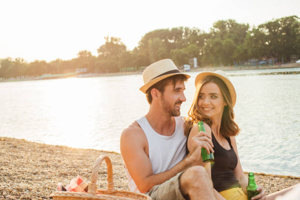istock Couple drinking beer on a picnic at the beach 974644142