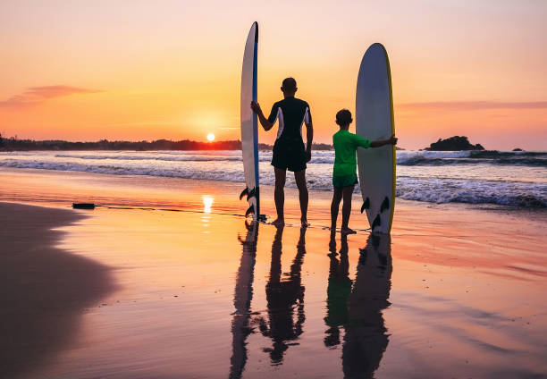 istock Father and son surfers stay on the sunset beach 974647186