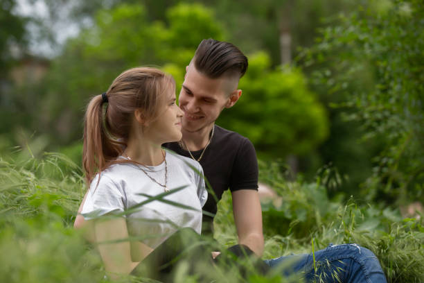 istock Loving young couple sitting on green grass 974647376