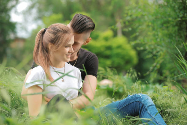 istock Loving young couple sitting on green grass 974647386