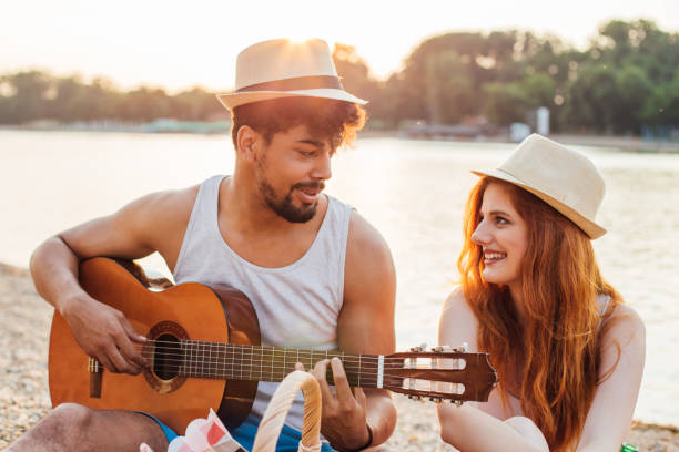istock Man wearing summer hat playing guitar for his girlfriend 974650182