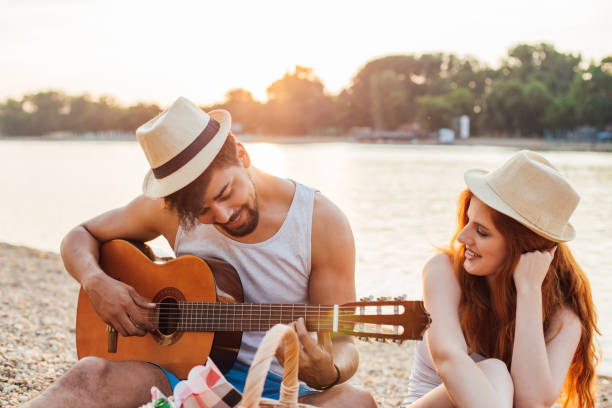 istock Handsome man playing guitar and beautiful woman looking at him 974650186