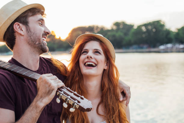 istock Young couple with a guitar laughing by the river 974651114