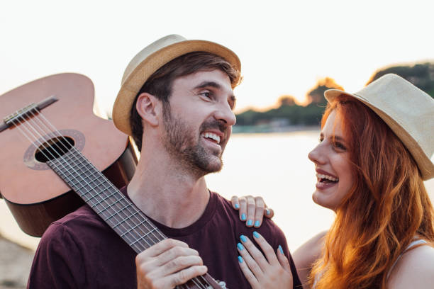 istock Young man holding a guitar looking at a woman touching his shoulder 974651198