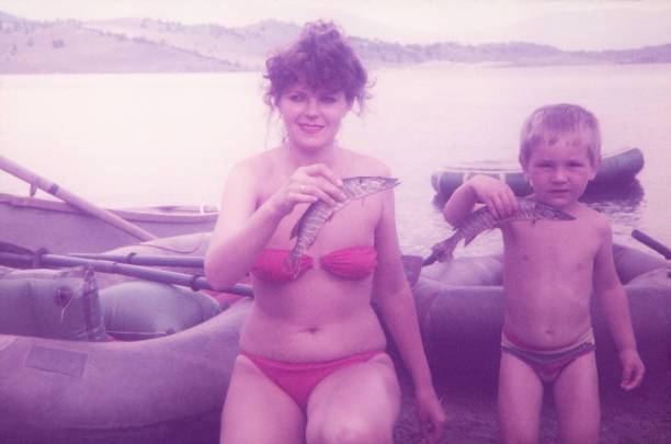 mère et ses piques fils de pêche sur le lac. - vacances photos photos et images de collection