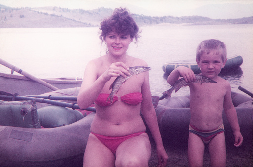 Family on vacation. A woman and her child holding a pike fish. Бухта Радости (Bay of Joy), Small sea, Lake Baikal, Irkutsk Oblast, Siberia, USSR. July of 1990. The original image was taken on Zenit-TTL 35mm SLR, lens 58mm Helios-44, ORWOChrom ISO 135 color reversal film.