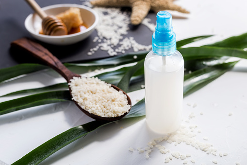 Homemade natural cosmetics for skin care and hair. Rice water in  bottle with batcher, fresh honey and seeds of rice.