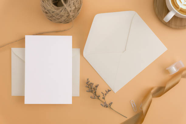 istock A wedding mock up concept. Wedding Invitation, envelopes, cards Papers on light brown background with ribbon and decoration. Top view, flat lay, copy space 974660842