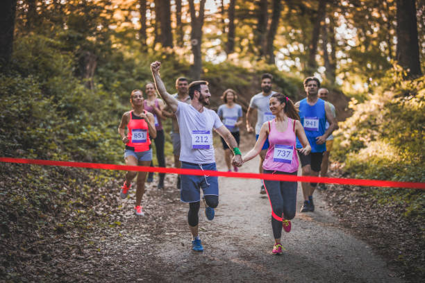 istock Happy marathon runners holding hands while running through finish line together. 974661062