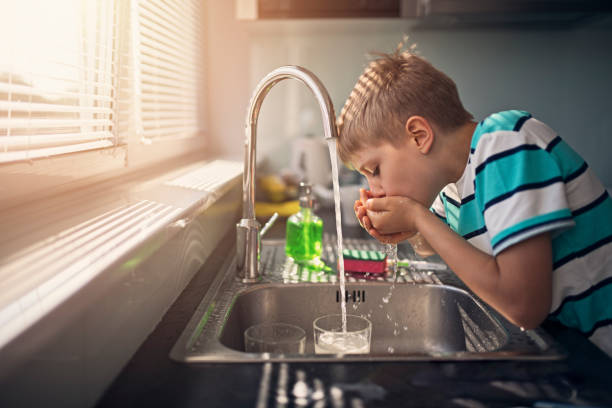 little boy bebiendo agua de grifo - agua potable fotos fotografías e imágenes de stock