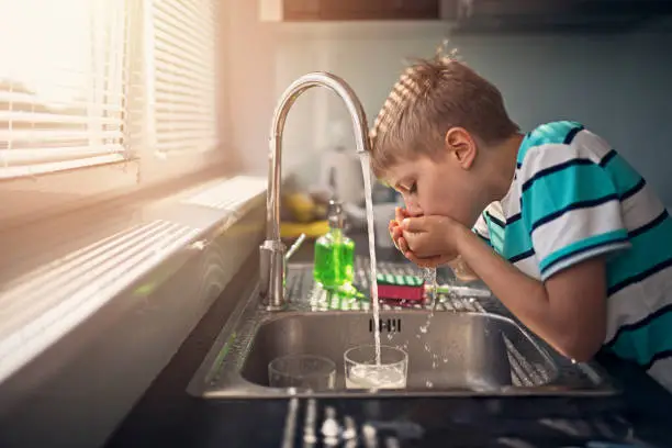 Little boy drinking tap water. Little boy aged 8 is drinking tap water in kitchen