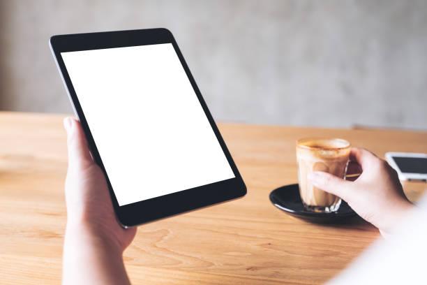 istock Mockup image of a woman holding black tablet pc with blank white desktop screen while drinking coffee in cafe 974676456
