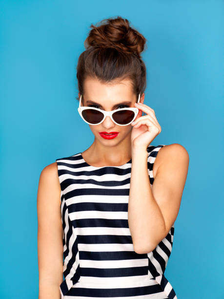 Studio shot of a beautiful young woman wearing glasses while posing against a blue background