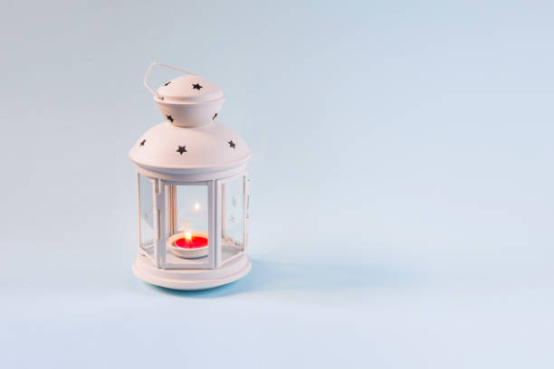 istock Red candle burning in a white Ramadan lantern on blue background 974679760