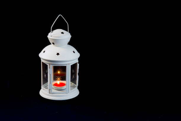 Red candle burning in a white Ramadan lantern on black background