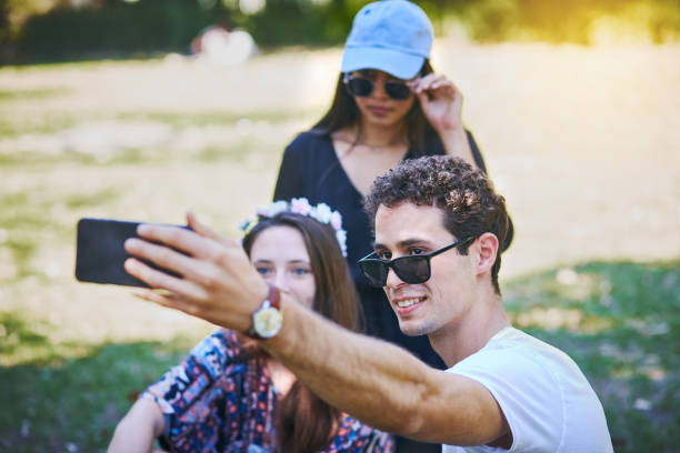 istock Three friends taking smiling selfie in park 974684266
