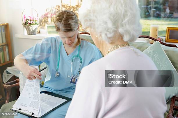 Medico Scrivendo Medical Report Per Donna Anziana In Una Casa Di Cura - Fotografie stock e altre immagini di Accudire
