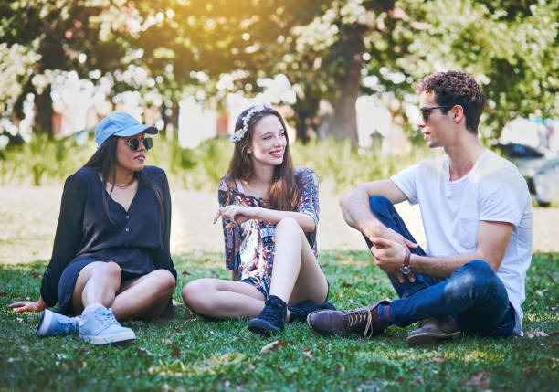 istock Three young people relaxing on lawn in sunny park 974687442