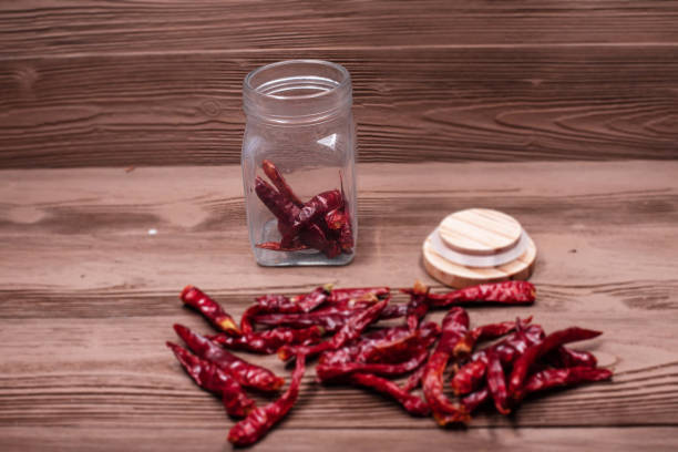 istock In selective focus of the opened glass bottle with dried pepper,blurry light design background. 974687526