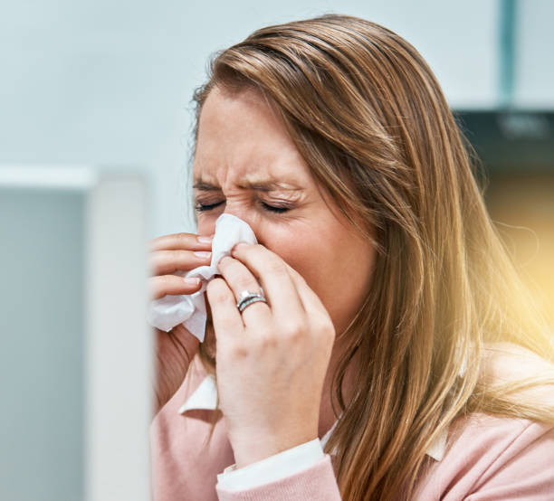 istock Woman office worker either sneezing or crying uses facial tissue 974691432