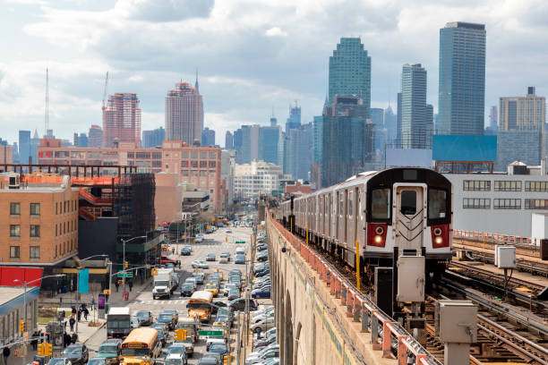 Subway Train Approaching  Elevated Subway Station in Queens, New York Train approaching  elevated subway station in Queens, New York. Financial buildings and New York skyline are seen in the background, on the left below can be seen a busy street full of cars at rush hour, cloudy, dramatic sky, USA. rail car stock pictures, royalty-free photos & images