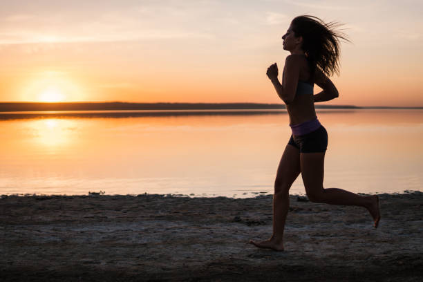 istock Woman Running on the Beach at Sunset 974706156
